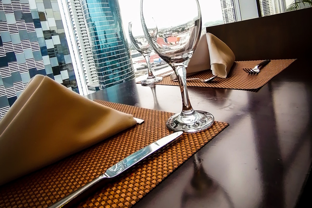 A wine glass and water glass on a restaurant table beside dinner plates.