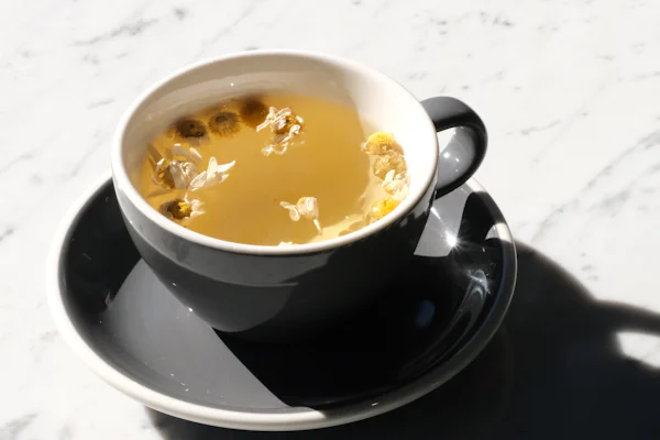 A calming cup of chamomile tea with blossoms in soft sunlight.