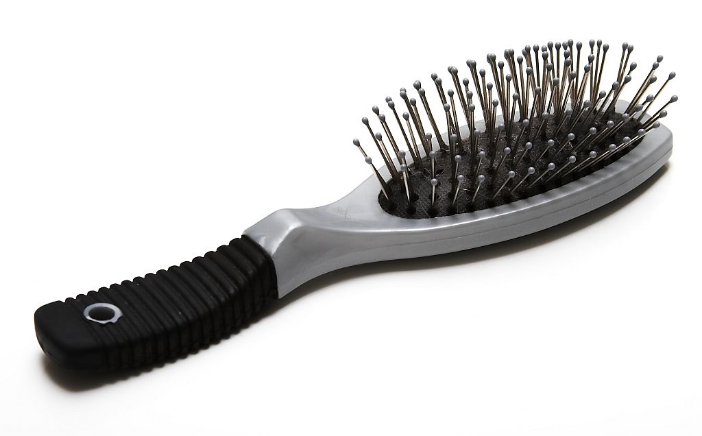A close-up photo of a hairbrush against a light background.