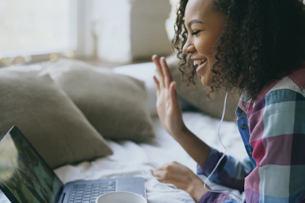 A woman on a telehealth-style video call using a laptop at home.